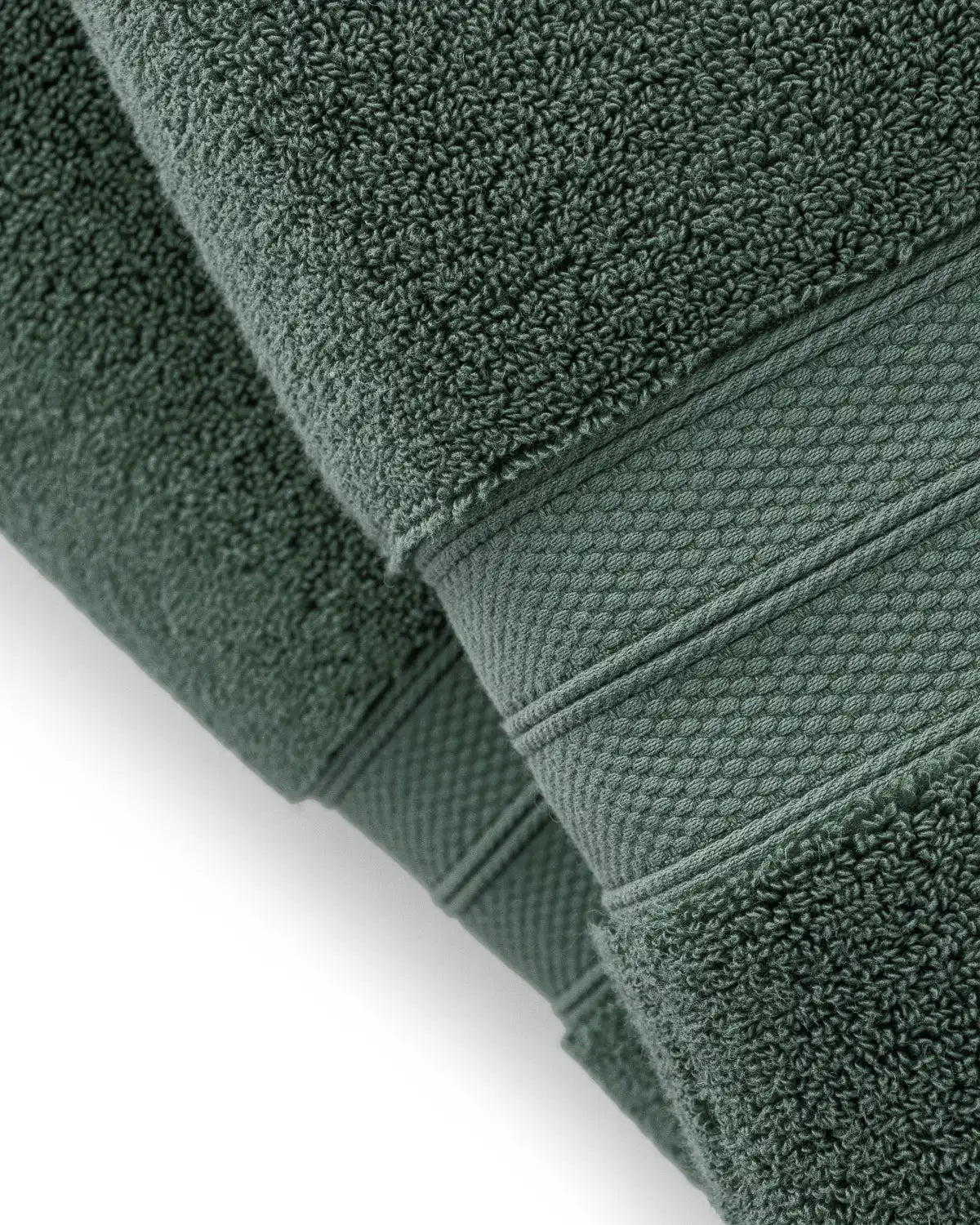 Stack of pine green modal cotton towels on a white background