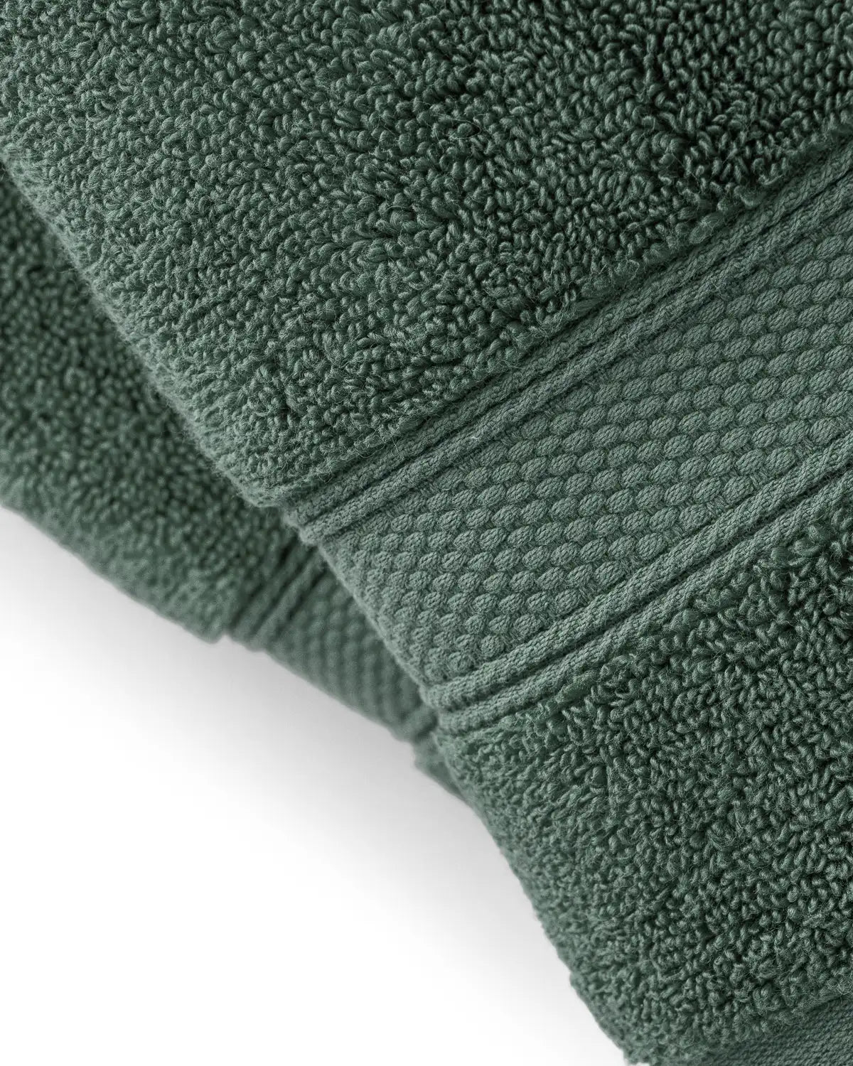 Close-up of a pine green modal cotton premium towel with textured edges on a white background