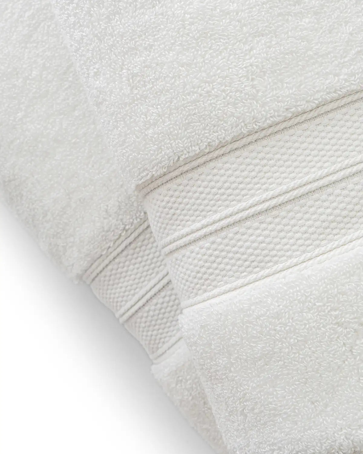Close-up of a folded white modal cotton premium towel with textured edges on a white background