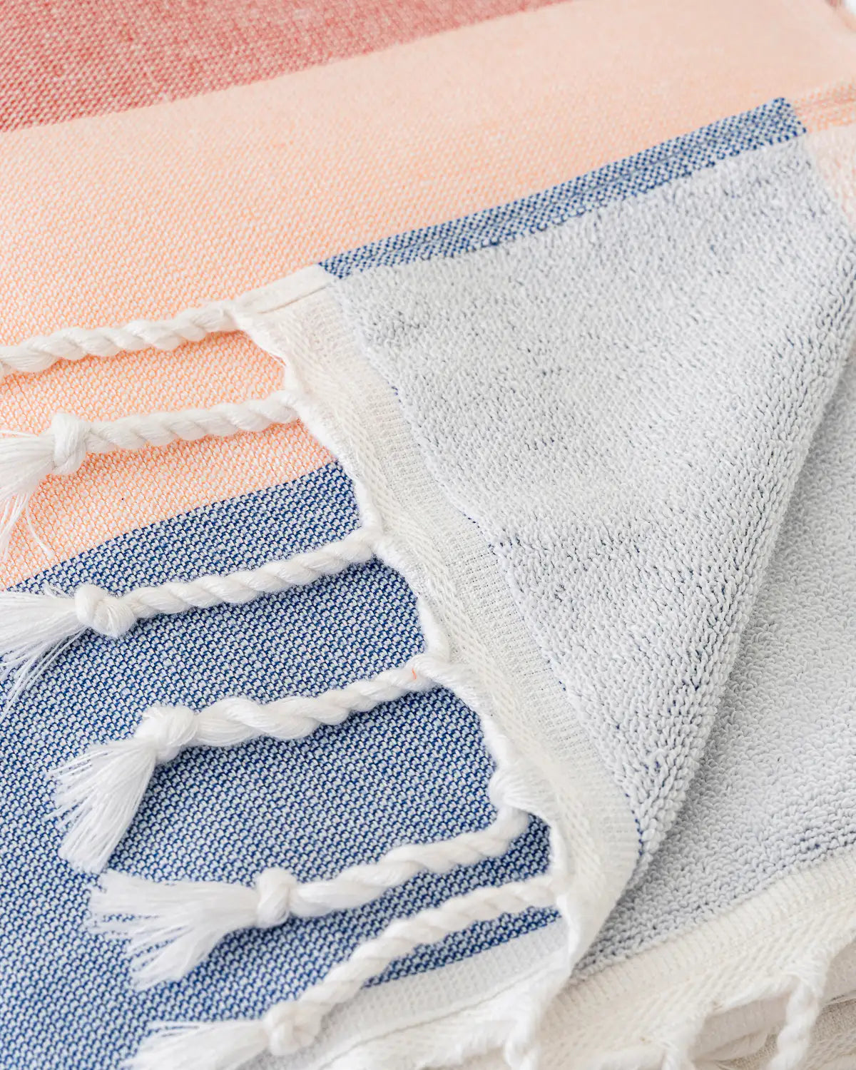 Close-up of a Soft Gradient Striped Beach & Pool Towel with tassels on a striped background