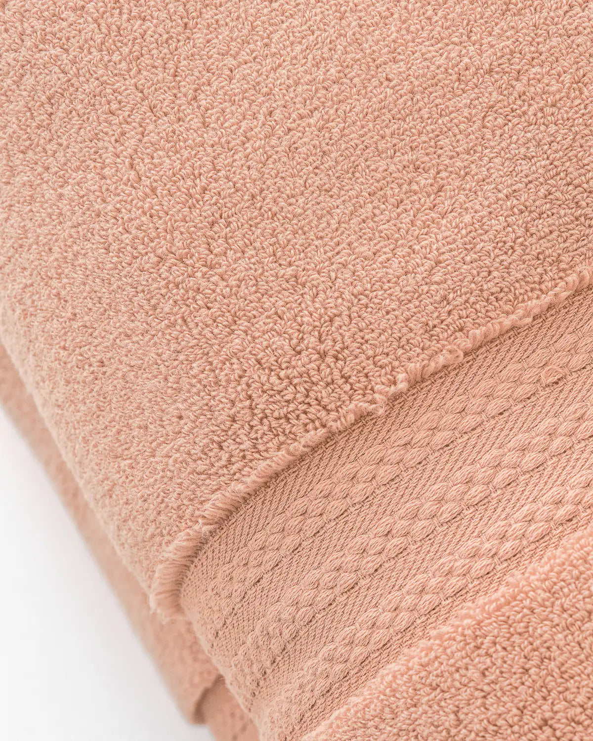 Close-up of a almond apricot ultrasoft cotton towel with textured surface on a white background