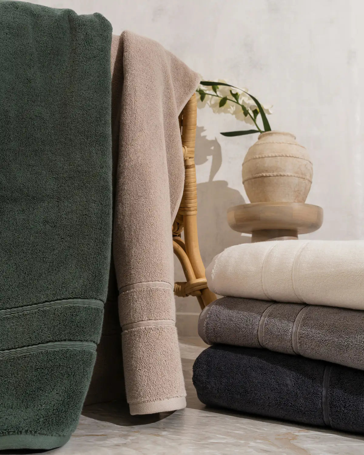 Stack of folded classic Turkish bath sheet in various colors with a vase and plant in the background.
