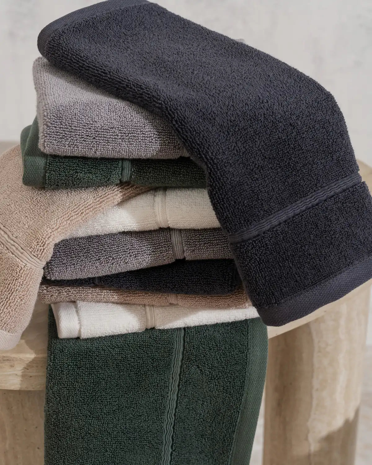 Stack of folded classic Turkish towels in various colors on a wooden surface.