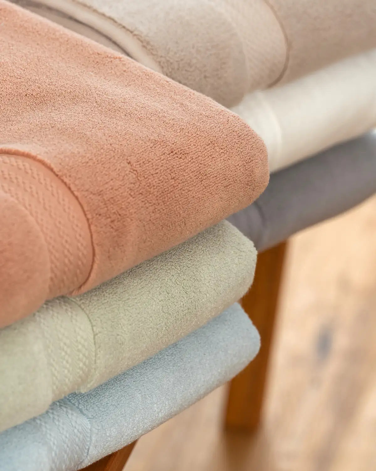 Colorful ultrasoft premium cotton towels lying on a wooden surface.