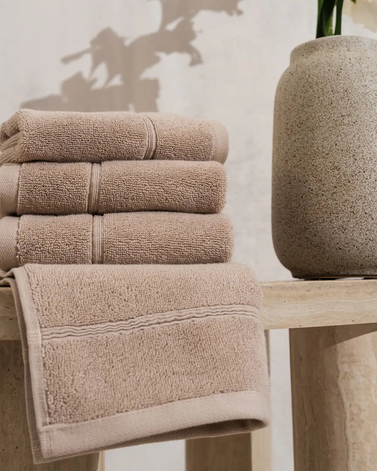 Stack of sandshell classic Turkish washcloth on a wooden surface with a vase in the background