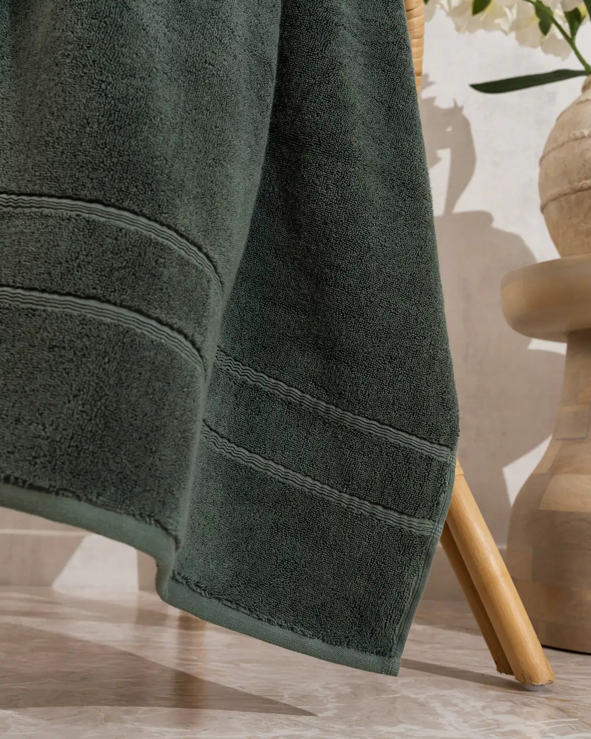 Pine green classic Turkish bath towel on a wooden surface with a blurred background