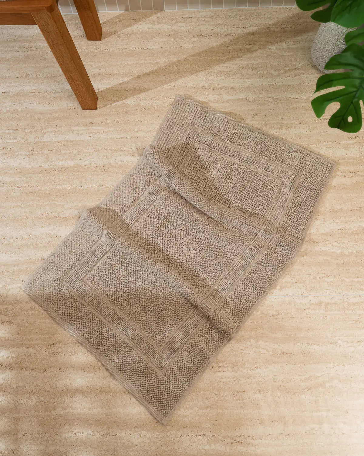 Sandshell High-Density Cotton Bath Rug on a wooden floor with a plant in the corner