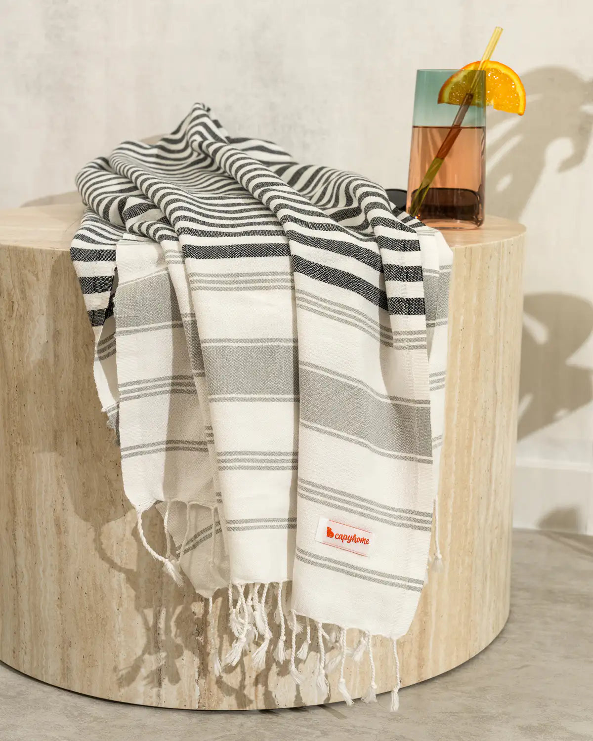 Ultra-Lightweight Multi-Purpose Beach Towel draped over a wooden stool with a drink in the background