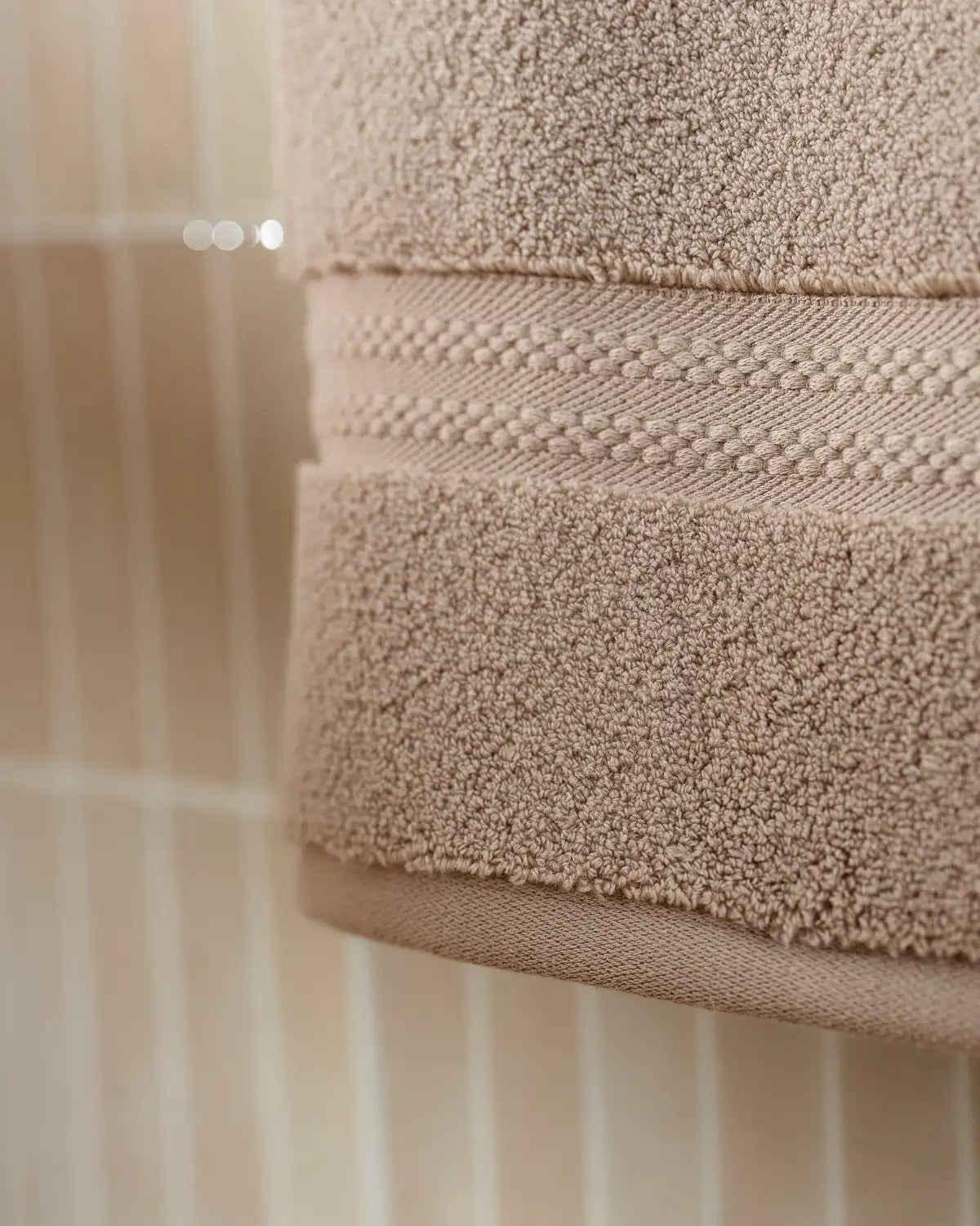 Stack of sandshell ultrasoft cotton hand towel on a towel rack with a blurred background