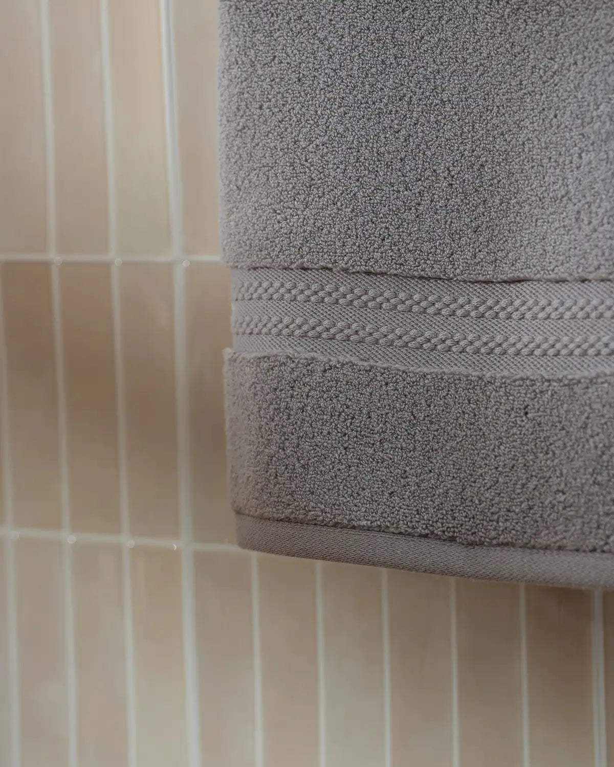Opal gray ultrasoft premium cotton towel hanging on a tiled bathroom wall