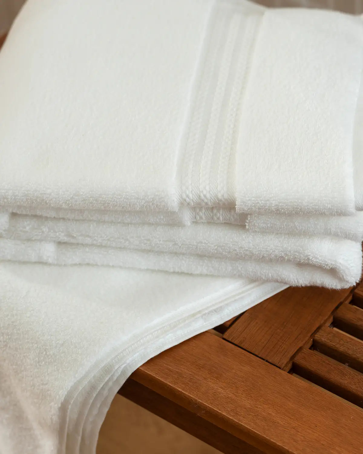 Stack of white ultrasoft Turkish cotton towels on a wooden surface