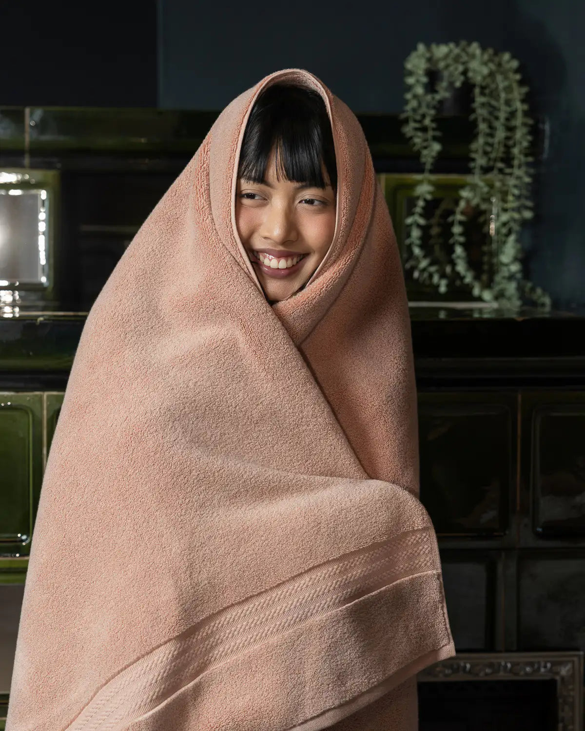Person wrapped in a almond apricot ultrasoft premium cotton bath towel with a dark background