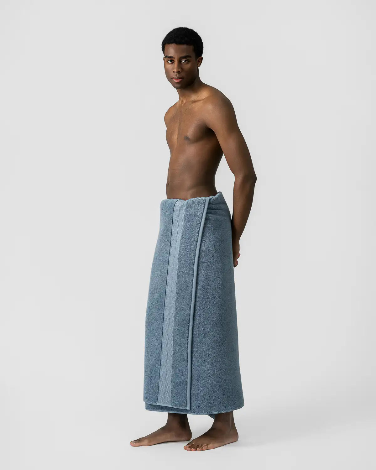 Man wearing a blue shadow modal cotton premium bath towel around his waist on a white background