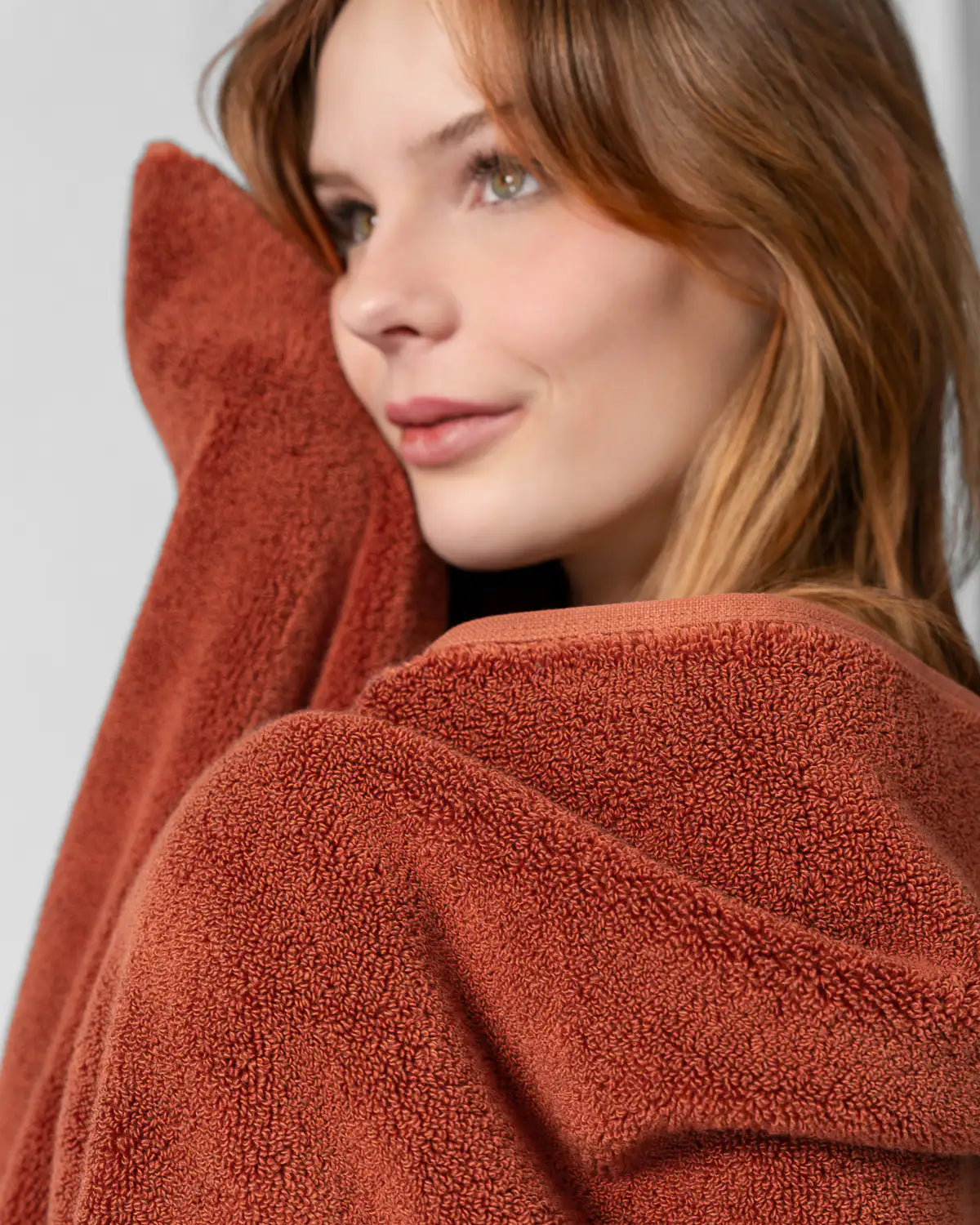 Woman wrapped in a sienna modal cotton premium towel against a white background