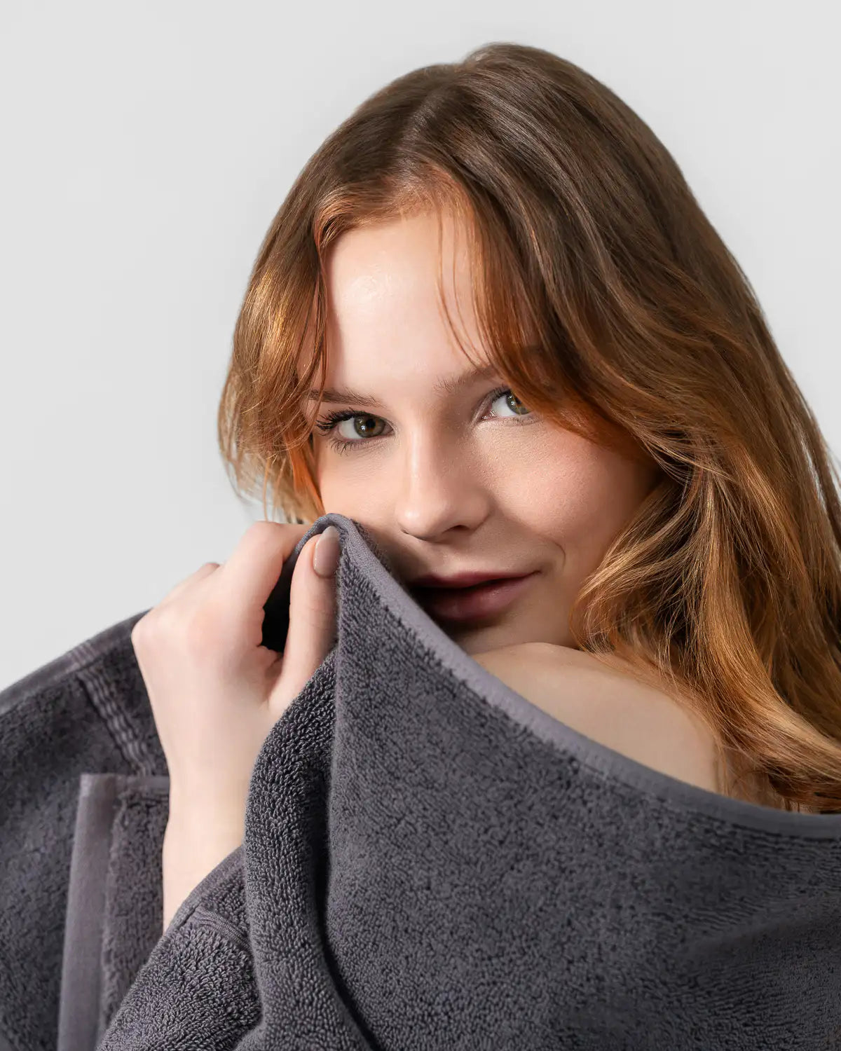 Woman holding a tornado gray classic Turkish towel against a plain background