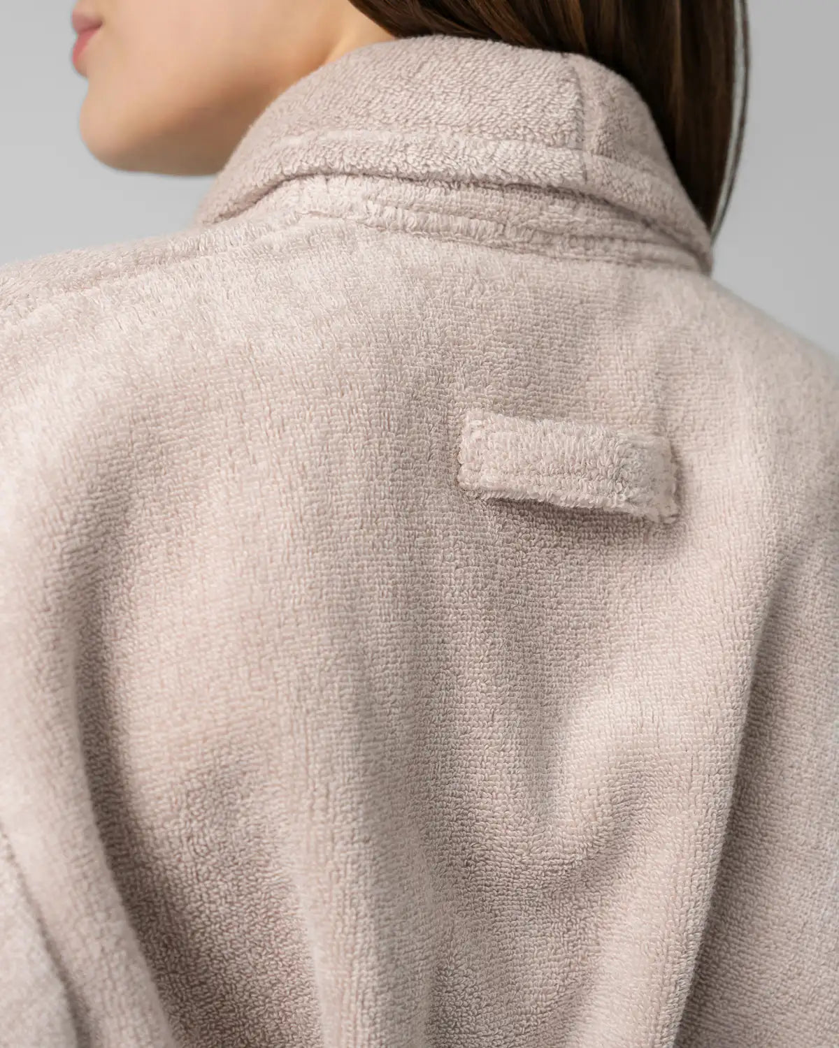Close-up of a textured sandshell ultrasoft bathrobe with a patch on a neutral background