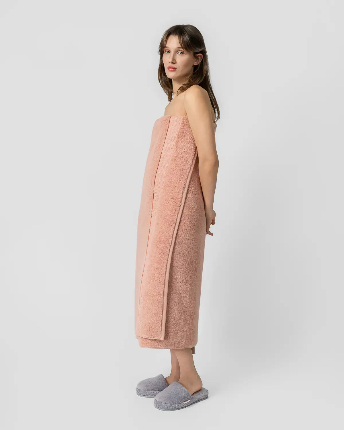 Woman wearing a almond apricot ultrasoft premium cotton bath sheet with a white background
