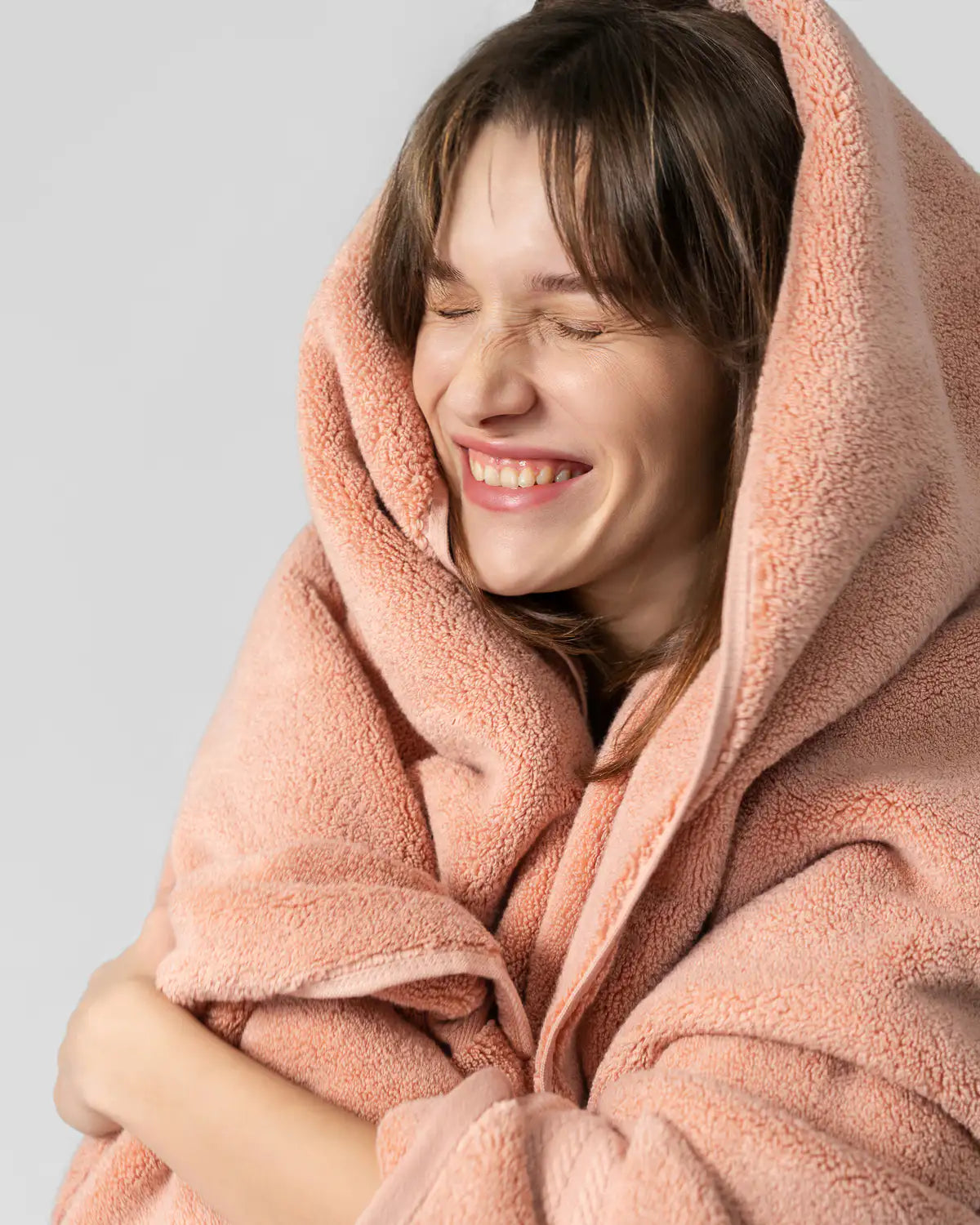 Person wrapped in a almond apricot ultrasoft premium cotton bath towel against a light gray background